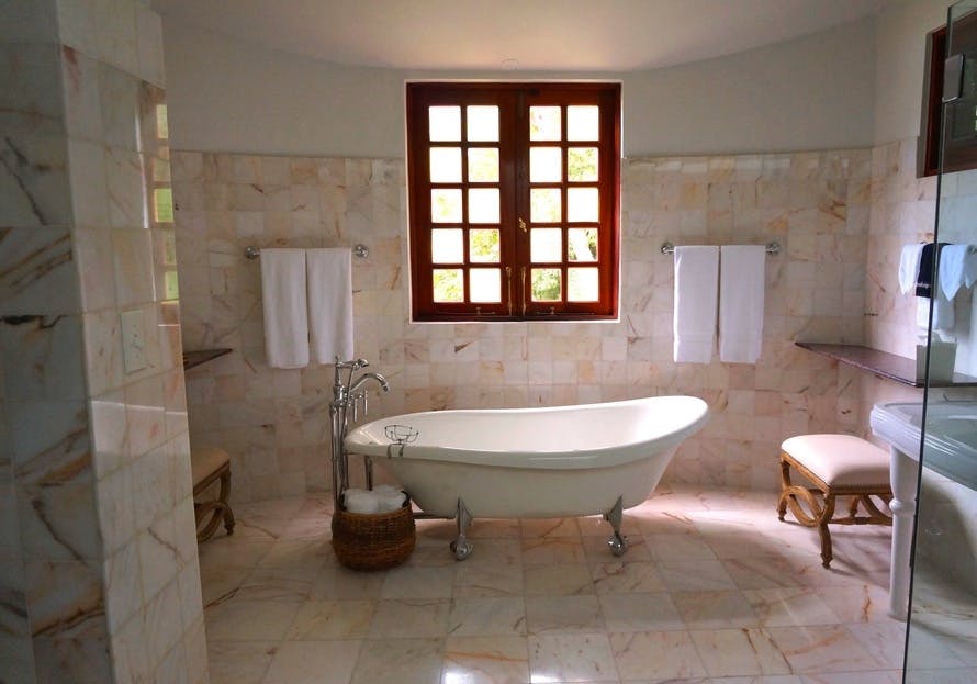 White Bathtub on White Tile Bathroom Near Brown Framed Clear Glass Window