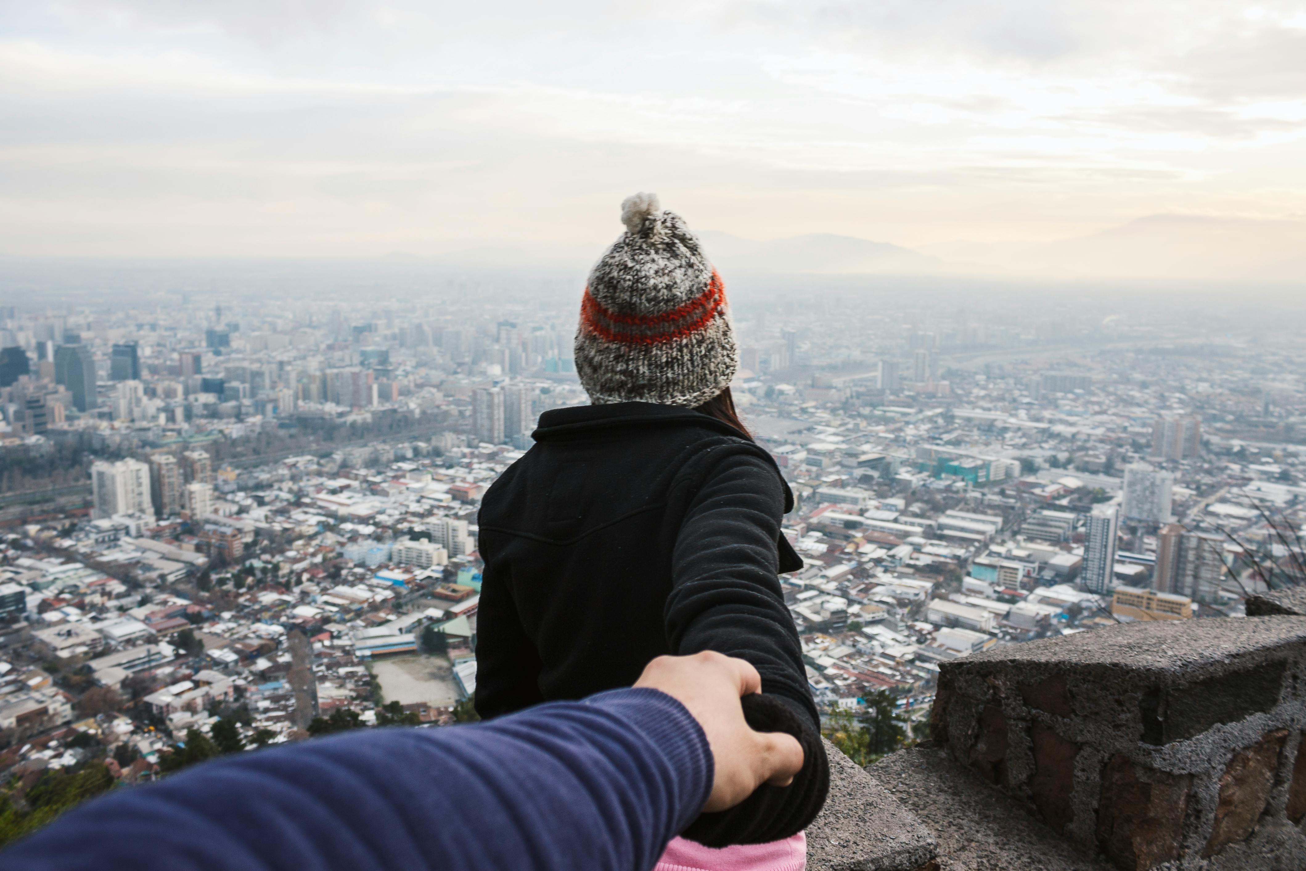 Couple holding hands in front of a city view