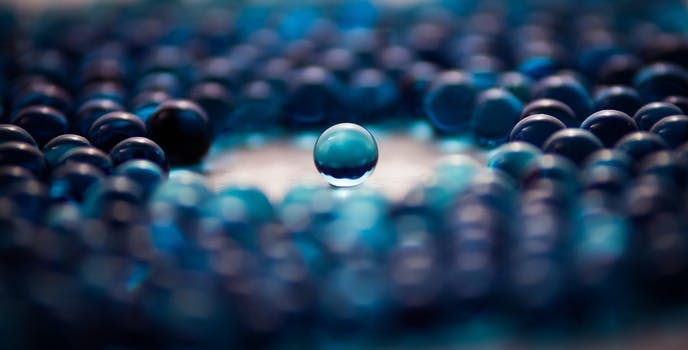 This picture shows a large number of blue opaque glass marbles. In the middle there is a round free space around a single marble located exactly in the center of the picture.