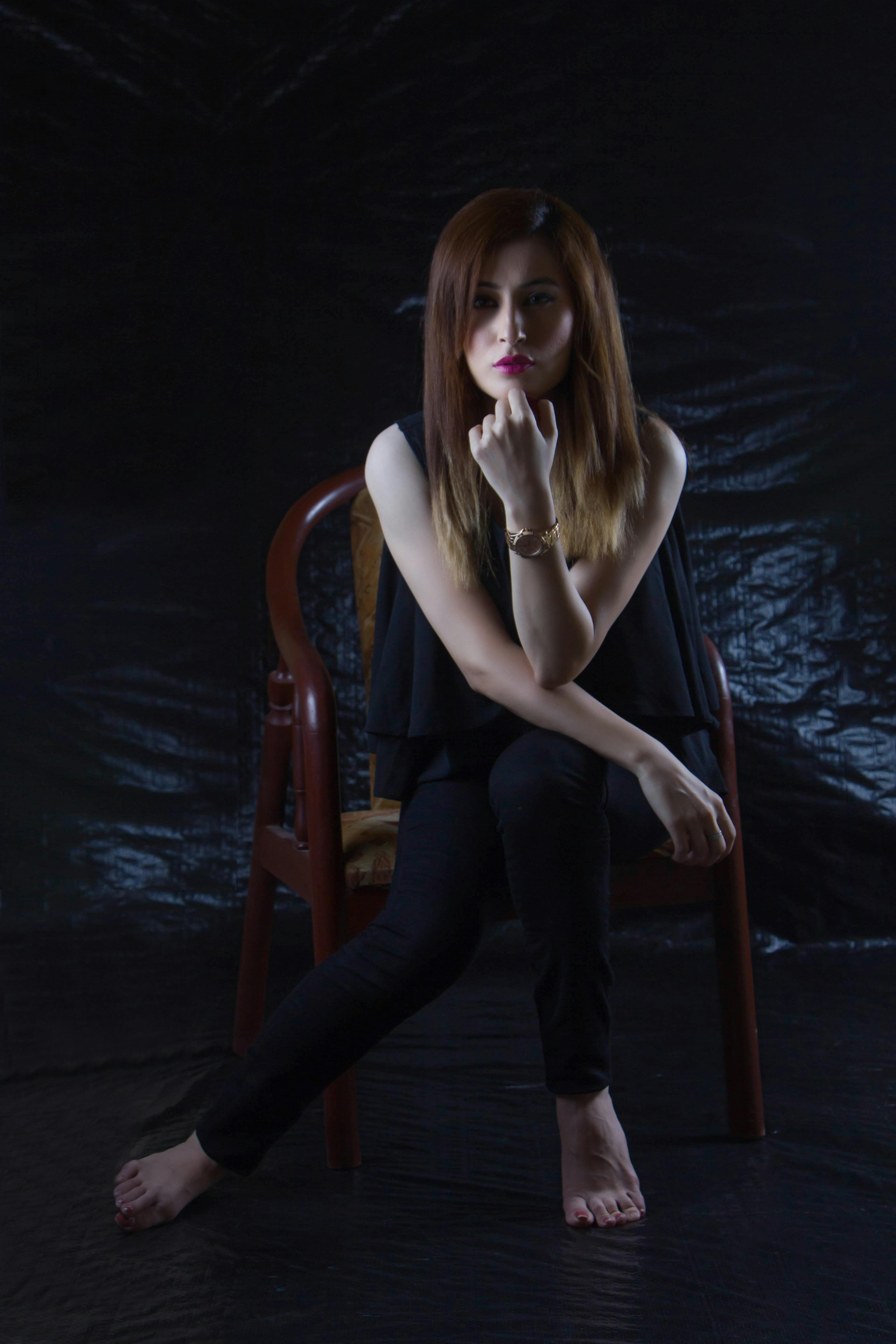 Woman Sitting on Brown Chair With Black Background · Free 