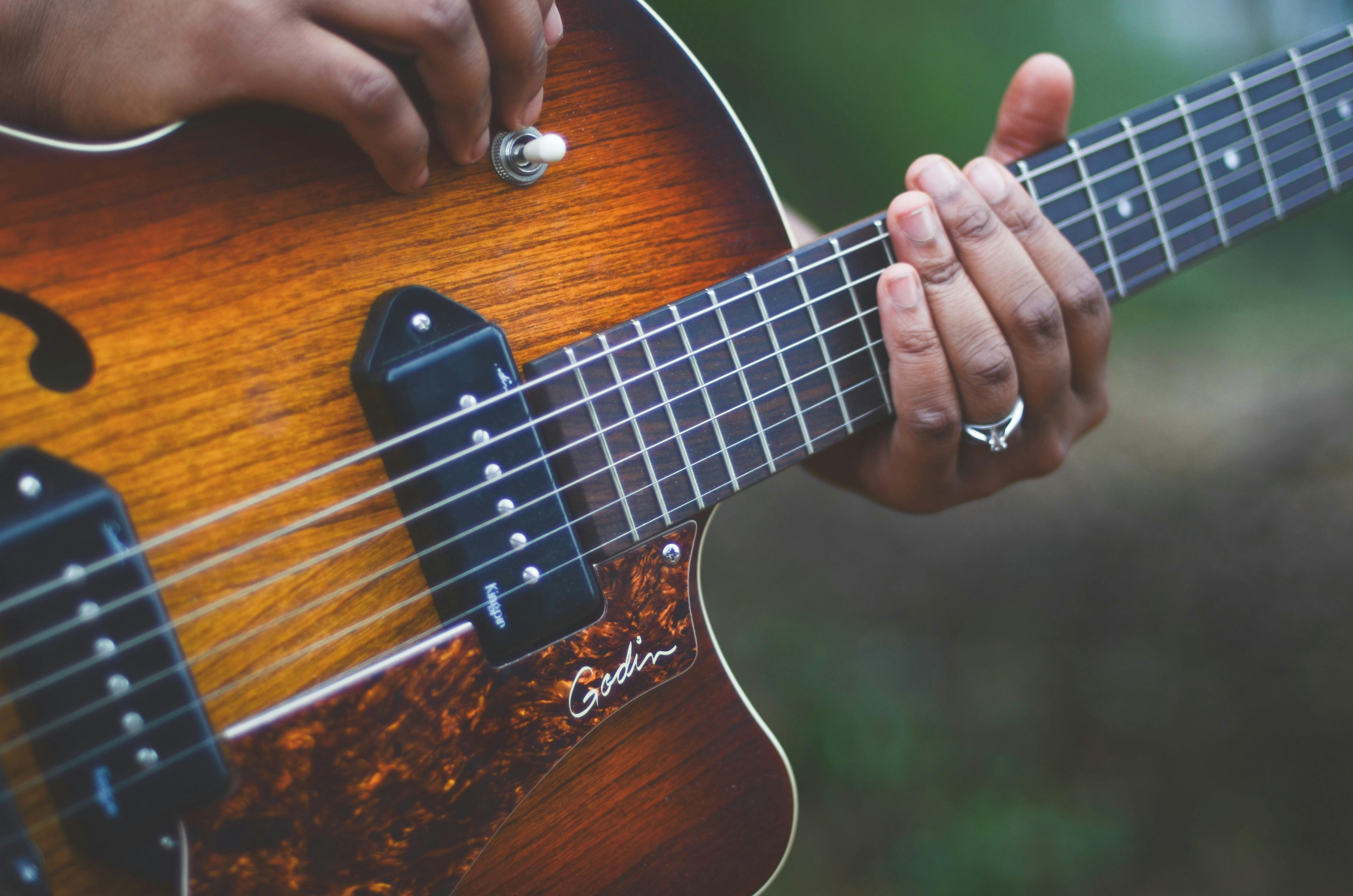 person-holding-brown-and-black-electric-guitar-free-stock-photo