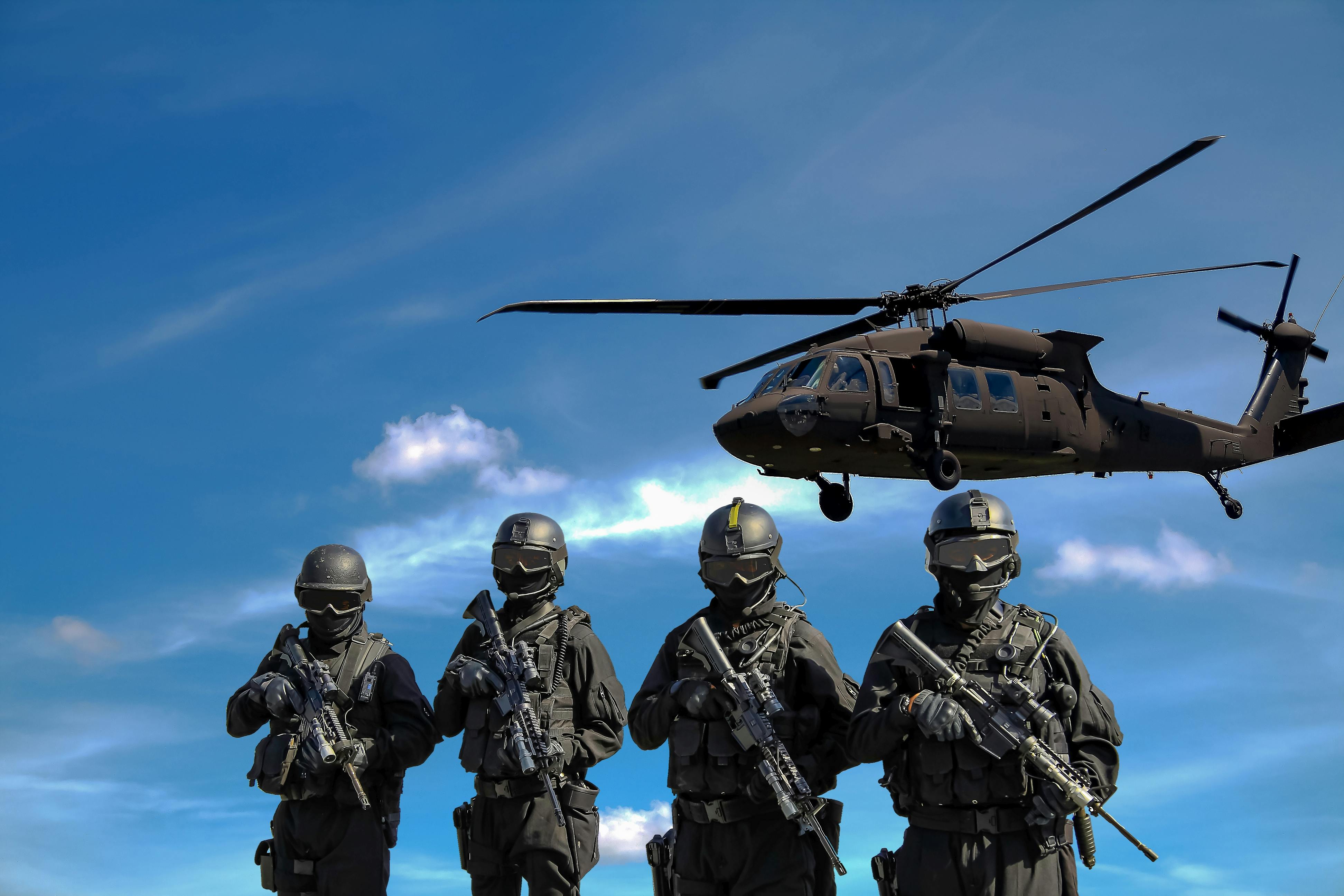 SWAT officers stand under a hovering SWAT helicopter.