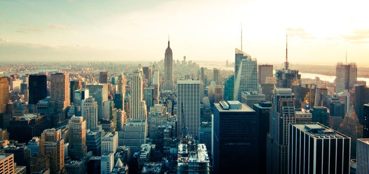 Great view of the New York City (NYC) skyline with a few high buildings and sun in the background.