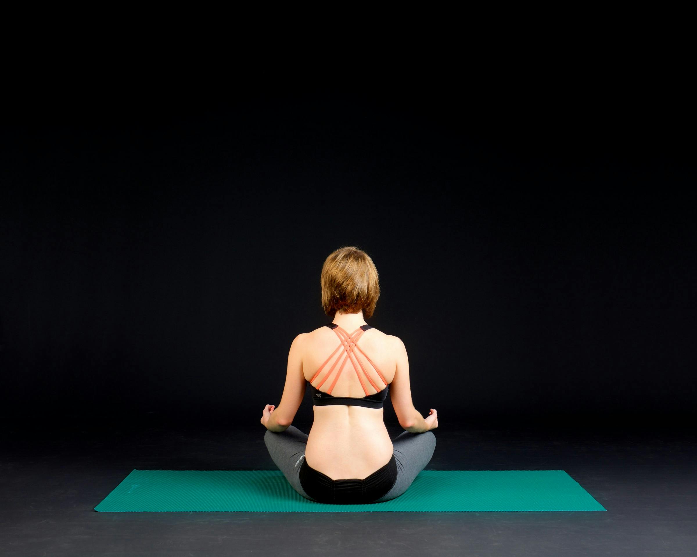 Woman practicing yoga on a teal mat.