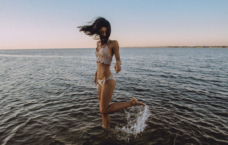 Woman Wearing Bikini Barefoot Standing on Sea Under Blue Sky