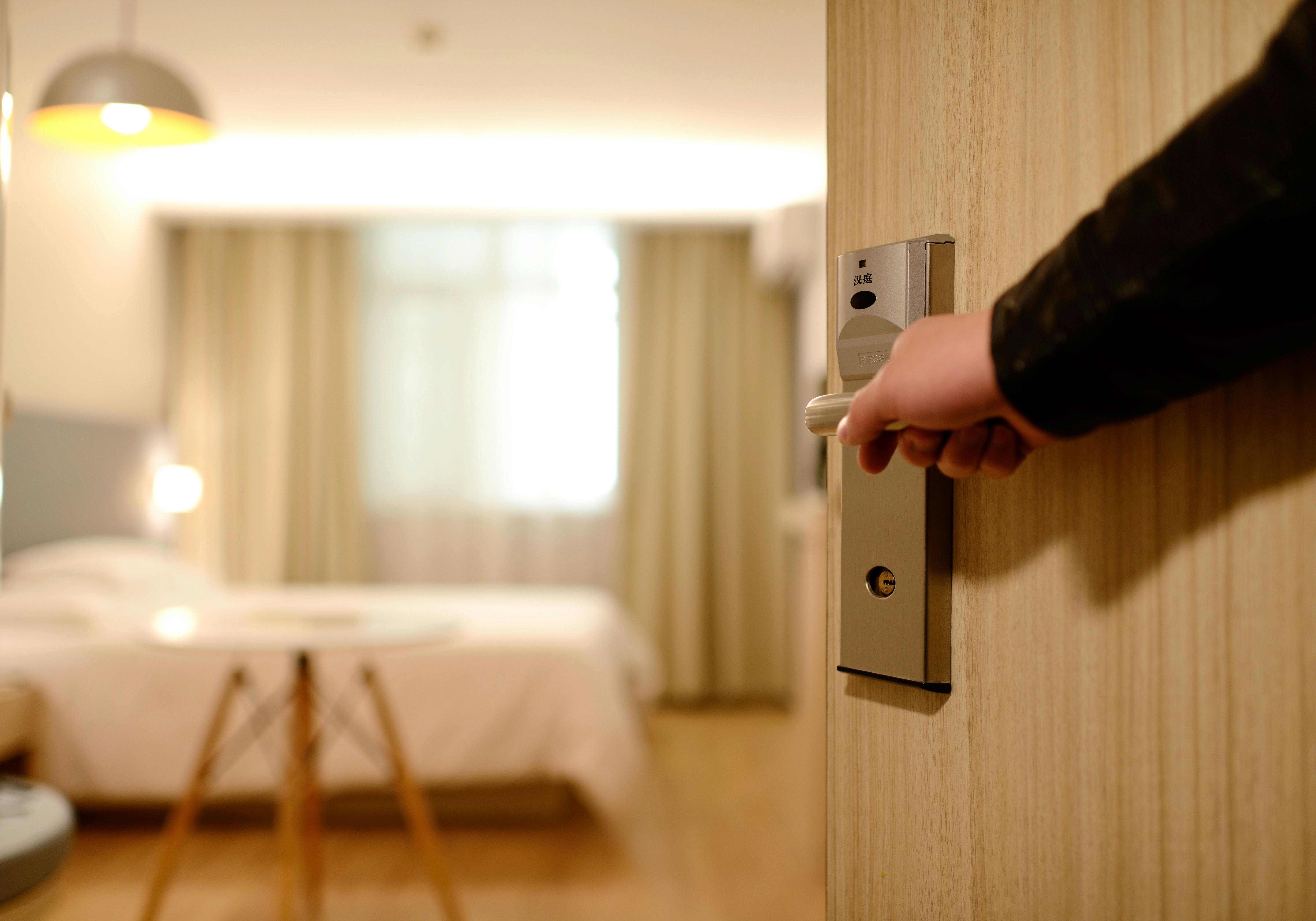 Image of a person opening a door to an organized bedroom to promote a healthy sleep space
