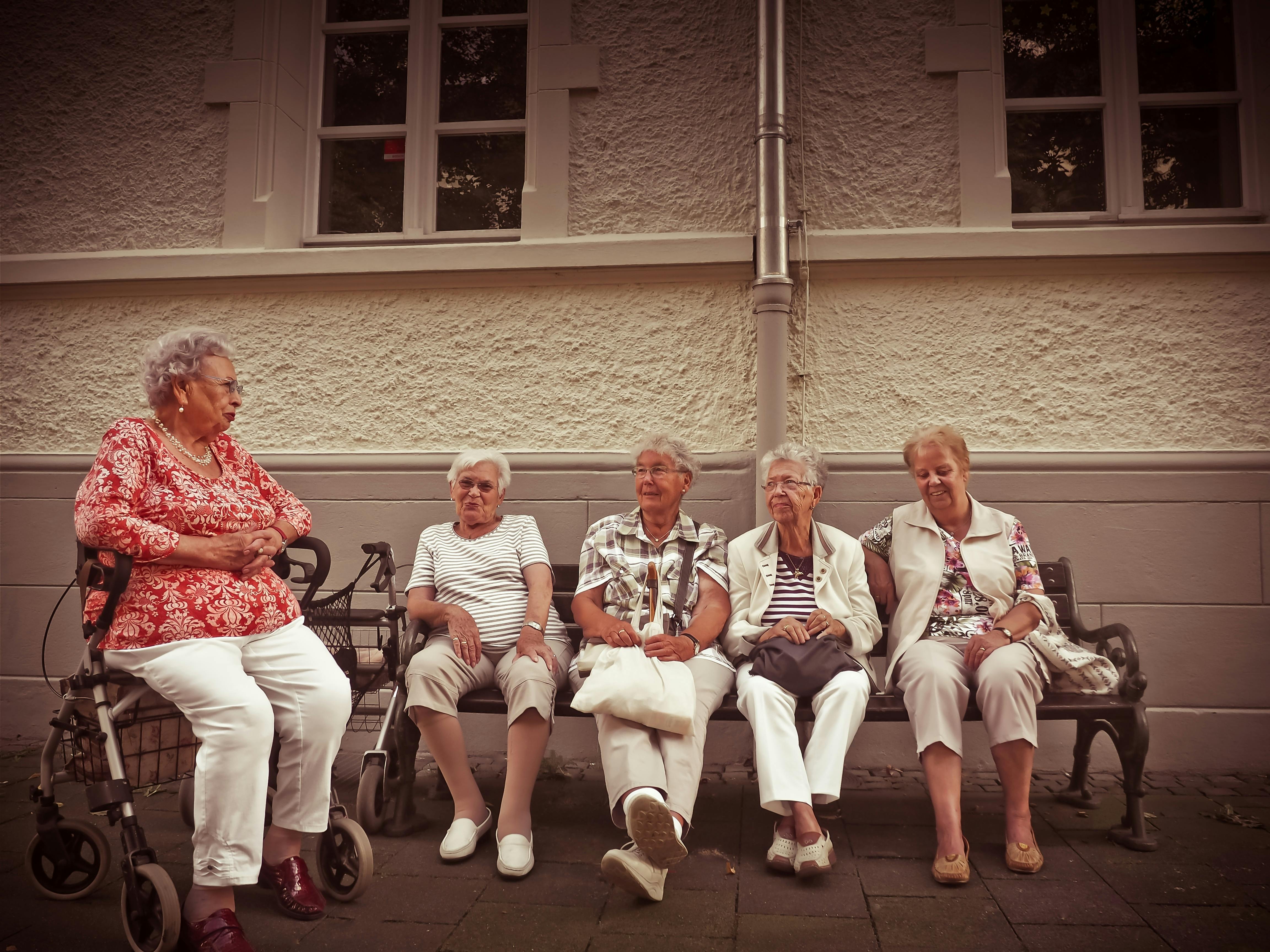 A group of retirees sitting outside of their retirement home.
