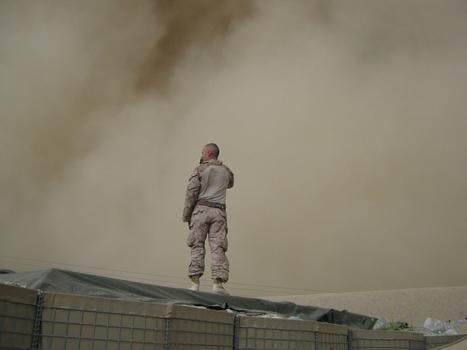 Soldier Standing on Top of a Black Tarp Covered Equipments
