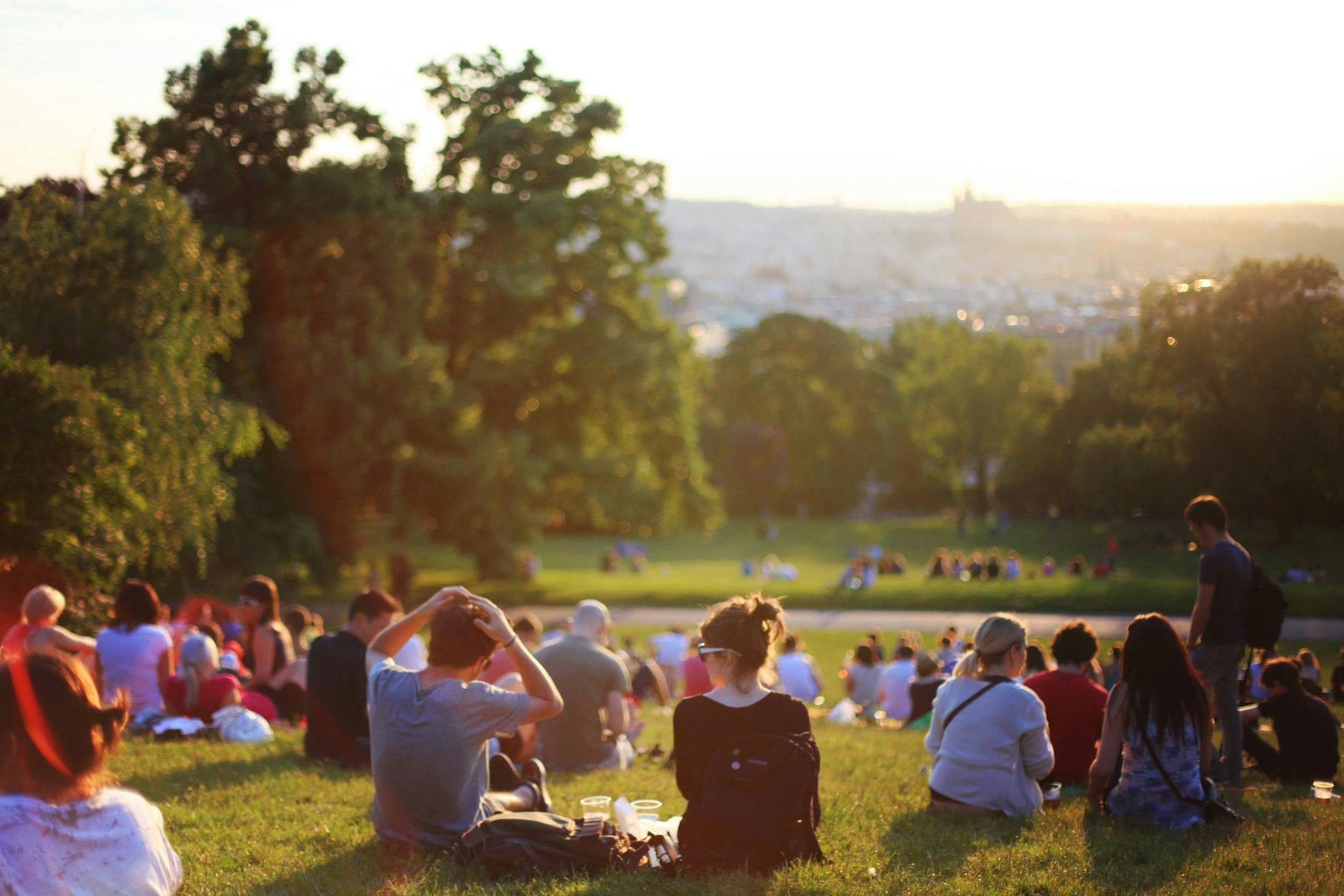 People enjoy sitting in the sun talking in a park.