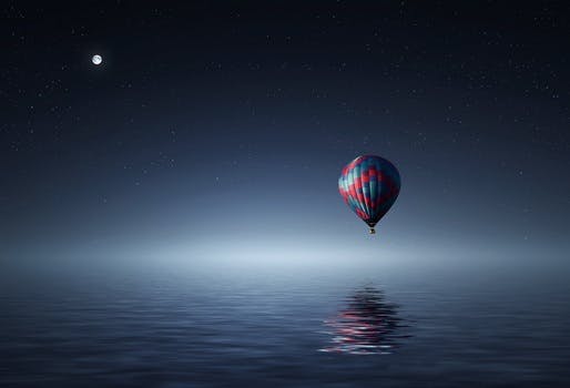 Red and Blue Hot Air Balloon Floating on Air on Body of Water during Night Time