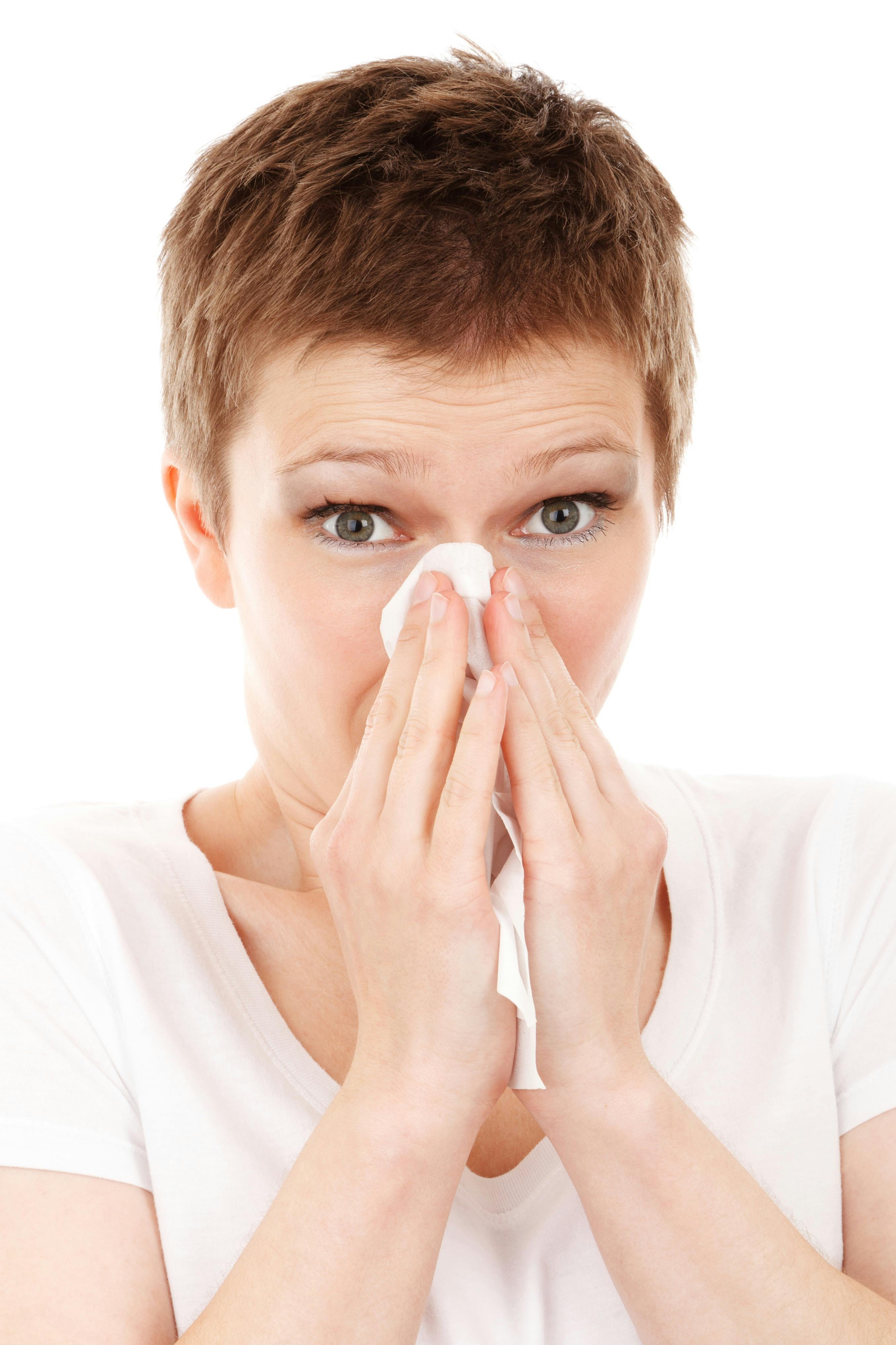 Woman blowing nose into Kleenex. 