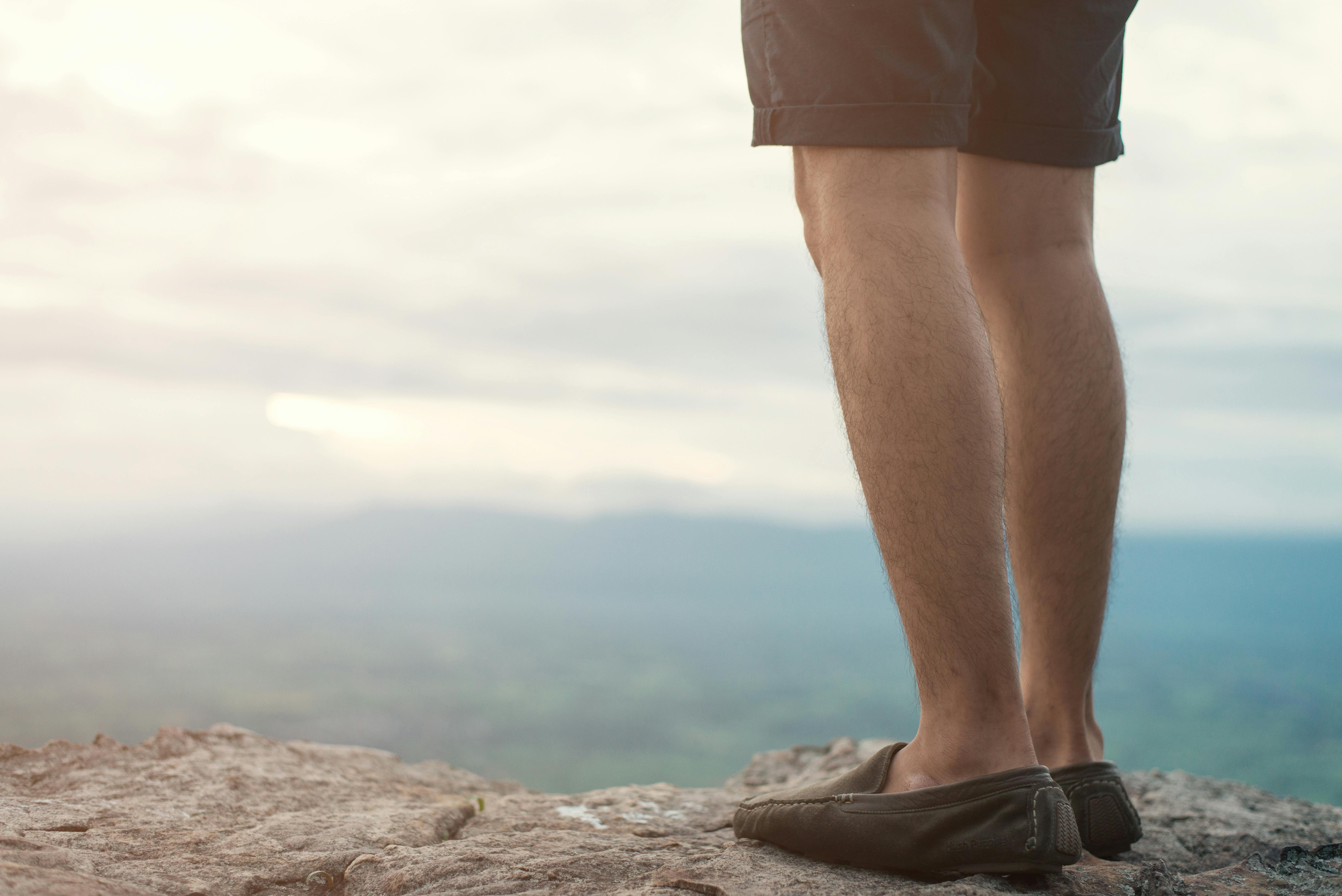 Man standing on a cliff looking off into the distance.