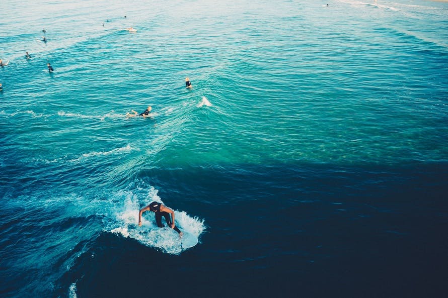Picture of people waiting for the wave with one person in the middle of catching the wave.