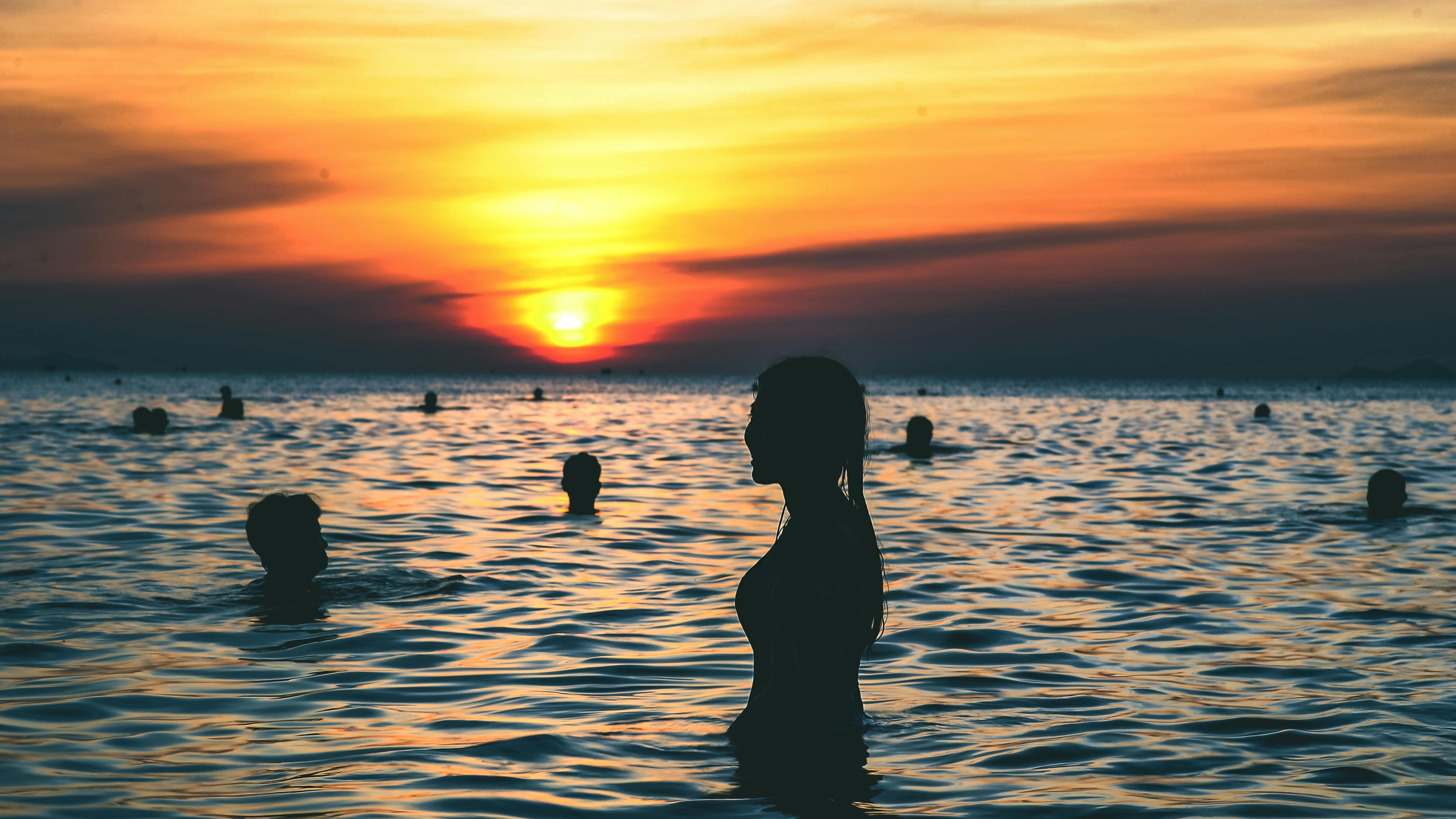 Silhouette Photography of People Swimming on the Beach during Golden