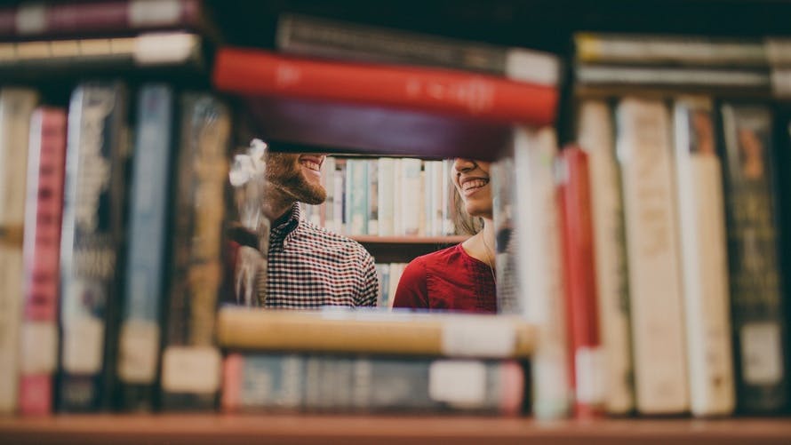 Couple Smiling Behind Books