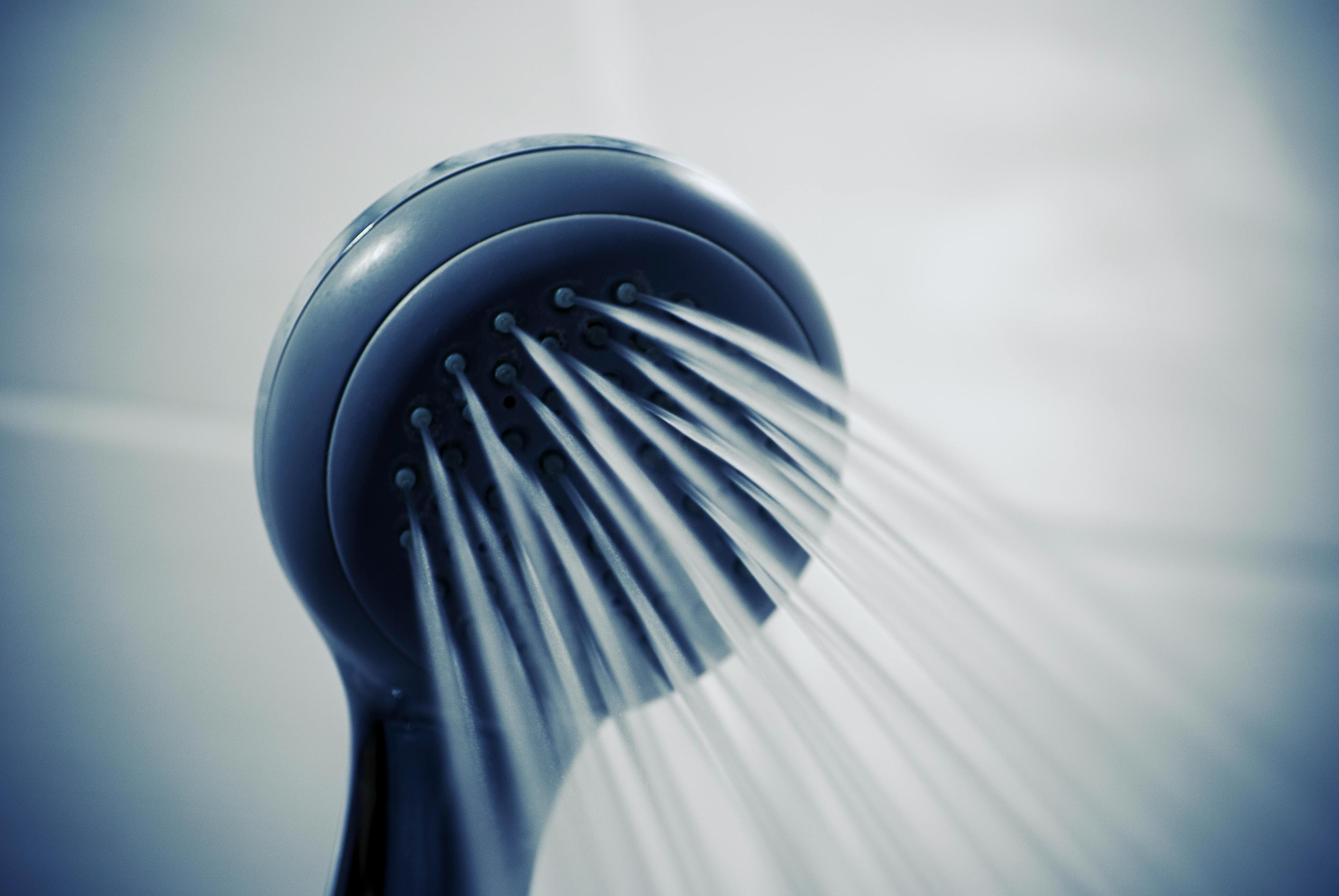 Close-up of shower head with water coming out.